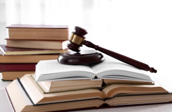 A stack of open books with a legal gavel on top